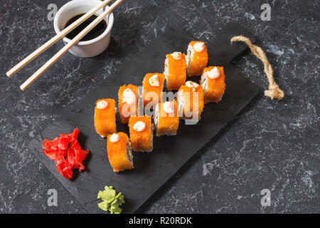 Rouleaux de sushi set servi sur ardoise noir sur fond sombre. Banque D'Images