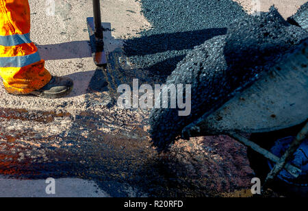 Frais de mise à niveau du travailleur au cours d'asphalte asphalte réparer ou de travaux de construction Banque D'Images