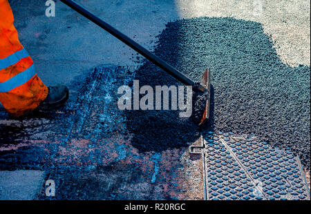 Frais de mise à niveau du travailleur au cours d'asphalte asphalte réparer ou de travaux de construction Banque D'Images