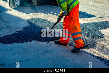 Frais de mise à niveau du travailleur au cours d'asphalte asphalte réparer ou de travaux de construction Banque D'Images