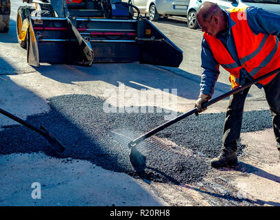 Frais de mise à niveau du travailleur au cours d'asphalte asphalte réparer ou de travaux de construction Banque D'Images