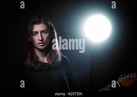 Studio portrait : un beau jeune homme aux cheveux long (musicien) rock avec guitare électrique Banque D'Images