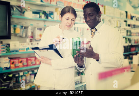 Hommes et femmes expérimentés les pharmaciens la prise d'inventaire des médicaments en pharmacie Banque D'Images