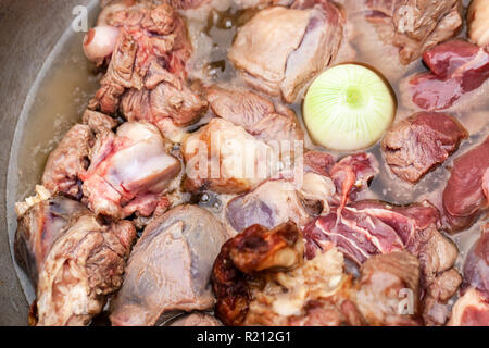 Morceaux d'agneau avec l'oignon entier ragoût dans un chaudron. La préparation de soupe Chorba sur feu ouvert, repas traditionnel pour de nombreuses cuisines nationales en Europe, Afrique Banque D'Images