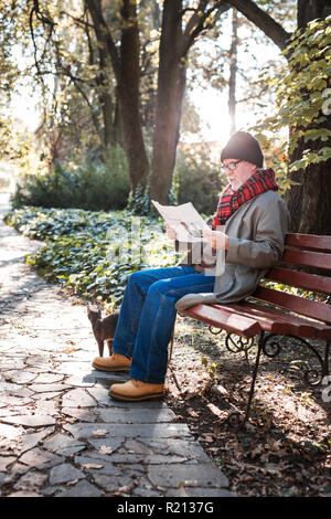 Homme d'âge intelligent de lire le journal dans le parc Banque D'Images
