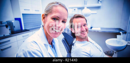 Femme dentiste writing on clipboard lors de l'interaction avec male patient Banque D'Images