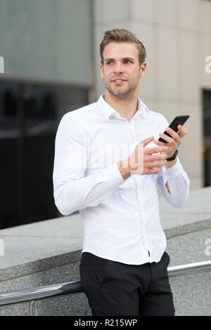 Contrôle de l'homme e-mails au matin contexte urbain. Businessman envoyer des messages ou envoyer des textos avec smartphone. Guy beau attractive businessman networking avec smartphone. Avantages du smartphone. Banque D'Images