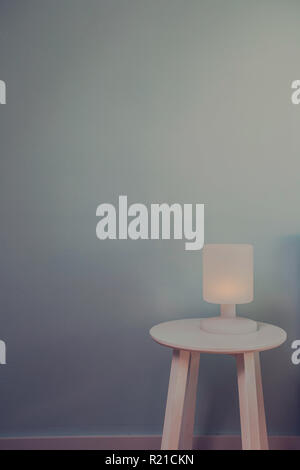 Lumière de Nuit lampe sur table en bois avec mur bleu pour le texte de l'espace. Vintage style effet photo. Concept minimal texture de fond. Banque D'Images
