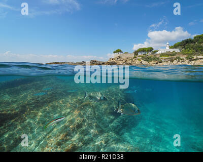 Côte Rocheuse avec un phare et le poisson sous l'eau, vue fractionnée de la moitié au-dessus et au-dessous de la surface de l'eau, Espagne, Costa Brava, Roses, mer Méditerranée Banque D'Images