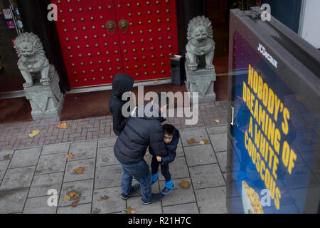 Une famille asiatique et shishi lions gardien à l'extérieur d'un restaurant chinois près de Elephant & Castle, le 9 novembre 2018, à Londres en Angleterre. Les lions de pierre, également appelé Shishi en chinois, sont souvent en paires en face des portes de bâtiments traditionnels chinois. Les lions gardien chinois, connu aussi sous le nom de lions en pierre dans l'art chinois, sont une représentation commune du lion dans la Chine pré-moderne. Ils sont soupçonnés d'avoir de puissants pouvoirs protecteurs mythique qui a traditionnellement se tenait en face de palais Impérial Chinois, tombes impériales, les bureaux gouvernementaux, les temples et les maisons des fonctionnaires du gouvernement un Banque D'Images