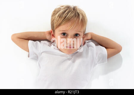Adorable petit garçon couché avec bras étendus Banque D'Images