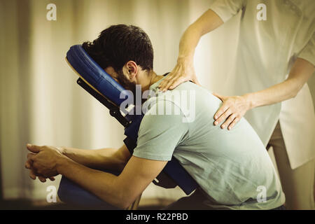 Physiothérapeute massage dos donnant à un patient Banque D'Images