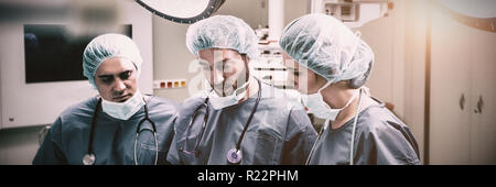 Chirurgiens discussing over digital tablet en salle d'opération Banque D'Images