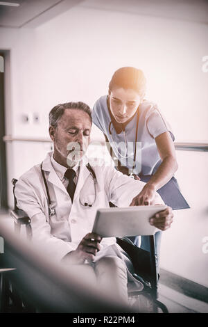 Médecin homme avec nurse talking sur tablette numérique Banque D'Images
