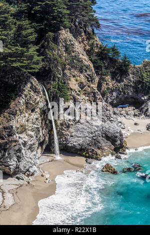 Plongeant sur une plage d'une falaise rocheuse le long de la côte de Big Sur en Californie, belle McWay Falls est dit être l'une des deux cascades, fabriquées main e Banque D'Images