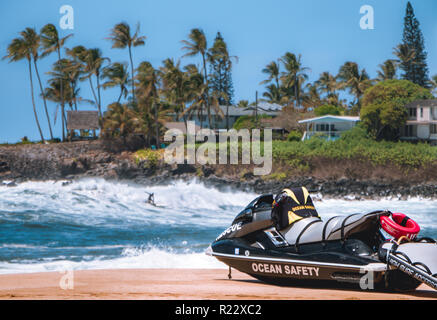 Un seul sufers hits une vague dans fround de roches et de maisons dans l'arrière-plan en blured sauveteur sauvetage jeux jetski sur la plage l'océan lit coffre-fort Banque D'Images