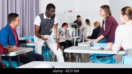 Friendly groupe multinational d'étudiants à parler en classe après avoir briser entre les leçons Banque D'Images