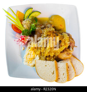 Appétissant jarret de porc cuit dans la bière et la choucroute servi avec sauce et le pain blanc. Isolated over white Banque D'Images