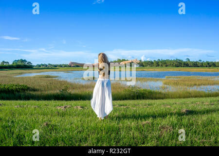 Jeune femme blonde normale aux cheveux longs retour en arrière dans l'article un beau paysage sur le terrain en plein air avec des mains lever les bras au ciel Banque D'Images