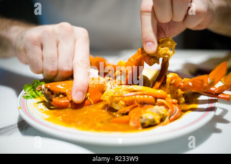 Les jeunes manger touristique style Singapour hot chili crab servi sur China Town. Plat de fruits de mer de l'Asie du sud-est. Banque D'Images