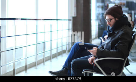 Close up.l'homme moderne avec le smartphone assis dans la salle d'attente de l'aéroport Banque D'Images