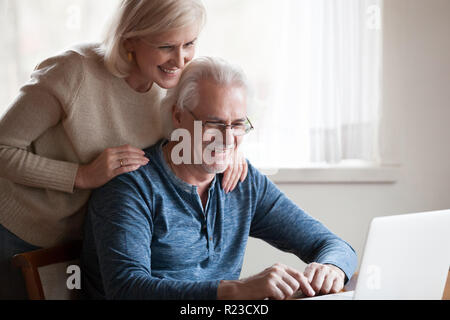 Heureux de mari à l'aide d'ordinateur portable montrant souriant femme quelque chose à l'écran, happy senior couple looking at computer, regarder des images ou l'amusement Banque D'Images