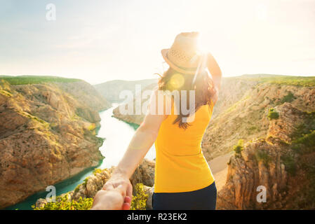 Jeune femme en jaune top hat et debout avec son dos à la caméra à bord de la falaise à la recherche au coucher du soleil sur le canyon de la rivière Zrmanja, Zadar, Croatie Banque D'Images