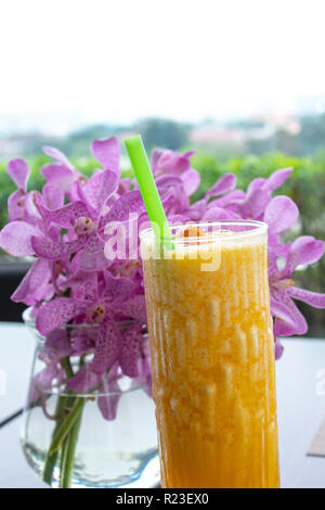 Jus d'orange en face de vase à fleurs d'Orchidées Banque D'Images