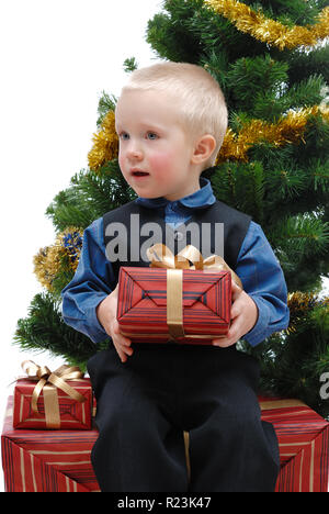 Petit garçon avec des cadeaux et l'arbre de Noël sur fond blanc, isolé Banque D'Images