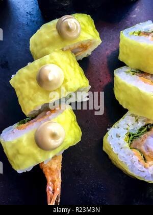 Délicieux sushis - fruits de mer avec du riz et jaune décoration sur la plaque noire. Banque D'Images