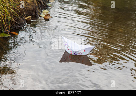 Papier blanc solitaire appelé bateau flottant sur un ruisseau de paix outdoor le sombre jour d'automne closeup Banque D'Images