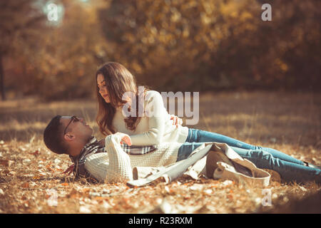 Joli couple est allongé sur le sol dans le parc sur le motif de feuilles d'automne Banque D'Images