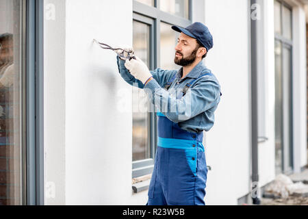 Câblage électrique de montage du constructeur sur la façade de l'immeuble pour l'éclairage extérieur Banque D'Images