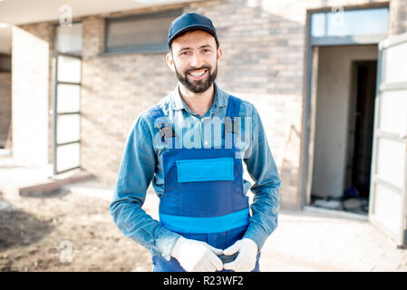 Portrait of a handsome builder en uniforme debout sur le fond à l'extérieur du bâtiment Banque D'Images