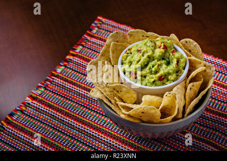 Croustilles de maïs et avocado guacamole trempette dans un bol sur une table Banque D'Images