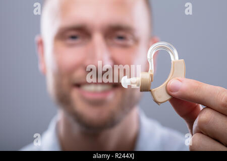 Close-up of a Happy Man Holding aide auditive Banque D'Images