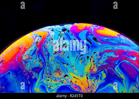Couleurs arc-en-ciel de près dans une bulle de savon qui ressemblent à des planètes ou des mondes de l'espace ou isolé sur un fond noir Banque D'Images