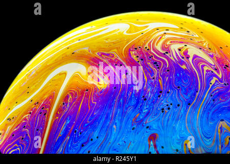 Couleurs arc-en-ciel de près dans une bulle de savon qui ressemblent à des planètes ou des mondes de l'espace ou isolé sur un fond noir Banque D'Images