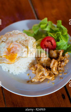 Préparé frais épicés asiatiques l'ail et le poivre calmars servis avec des oeufs au plat sur le riz au jasmin dans un restaurant local sur l'île de Koh Mook. Thai traditionnelle cuis Banque D'Images