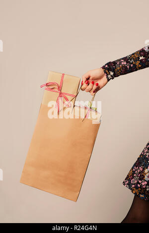 Libre d'un young caucasian woman holding a paper panier plein de cadeaux contre un fond blanc, avec un peu d'espace vide en haut Banque D'Images