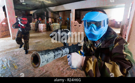 Portrait de l'équipe bleu happy cheerful joueur qui vise à adversaires sur le terrain de paintball.