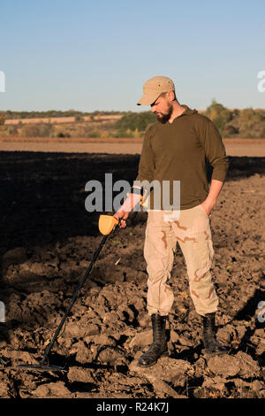 Le sapeur militaire avec un détecteur de métal examine le sol dans le domaine de la présence de mines Banque D'Images