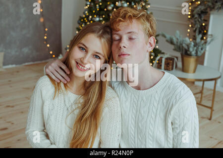 Beautiful happy young couple sitting and smiling at camera à la veille de Noël Banque D'Images
