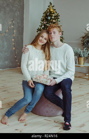 Beautiful happy young couple sitting and smiling at camera à la veille de Noël Banque D'Images