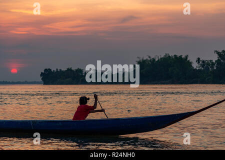 Don Det, Laos - Avril 22, 2018 aviron : un bateau en bois sur le Mékong au coucher du soleil près de la frontière cambodgienne Banque D'Images