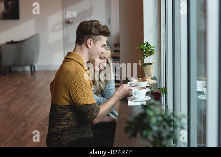 Couple using mobile phone in cafe Banque D'Images