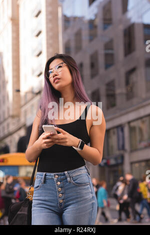 Woman using mobile phone in city Banque D'Images