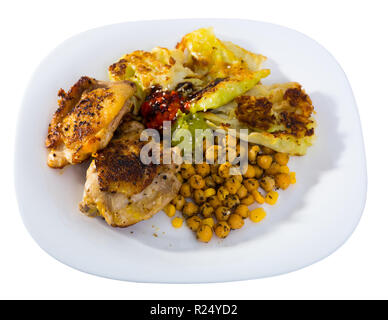 Cuisses de poulet au four avec des feuilles de chou battues, le pois chiche et les sauces servis sur plaque blanche. Plus isolé sur fond blanc Banque D'Images