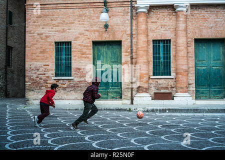 Les garçons jouent au football dans la rue de l'Urbania, l'Italie, l'Europe. Banque D'Images