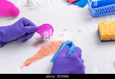 Les mains dans les gants de détachant liquide appliquée. Banque D'Images